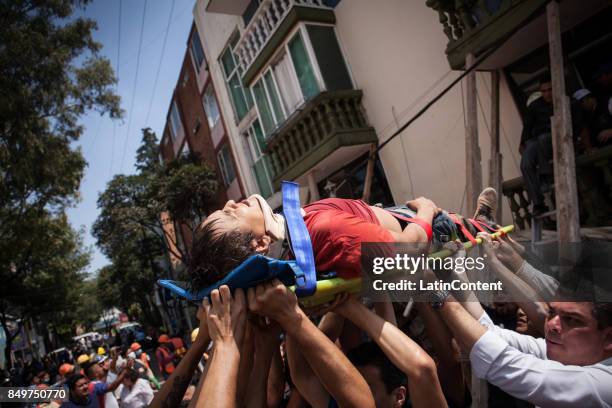 Rescuers and residents assists an injured victim amid the ruins of a building knocked down by a magnitude 7.1 earthquake that jolted central Mexico...