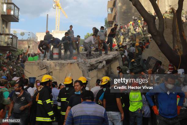 Rescuers and residents look for victims amid the ruins of a building knocked down by a magnitude 7.1 earthquake jolted central Mexico damaging...