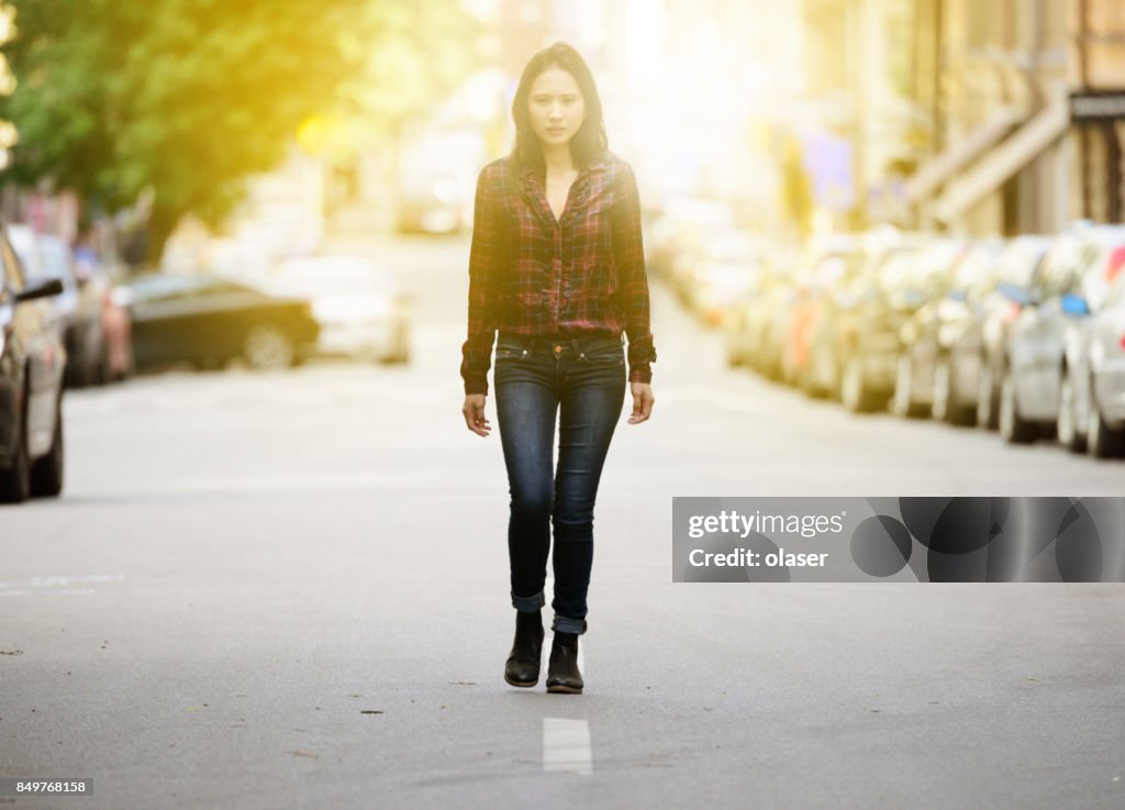 Woman walking Stockholm city street sunset in background