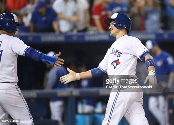 Darwin Barney of the Toronto Blue Jays is congratulated by Ryan Goins after hitting a two-run home run in the sixth inning during MLB game action...