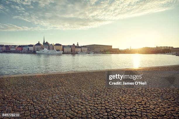 riverside paving with distant buildings in the city at sunset, stockholm, sweden - promenade stock-fotos und bilder