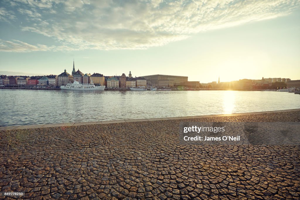 Riverside paving with distant buildings in the city at sunset, Stockholm, Sweden