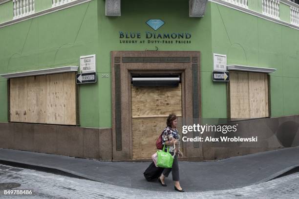 Woman passes a boarded up business as residents prepare for a direct hit from Hurricane Maria on September 19, 2017 in San Juan, Puerto Rico. Puerto...