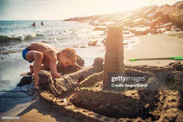 kleiner junge sandburg am strand von italienischen bauen - kind sandburg stock-fotos und bilder