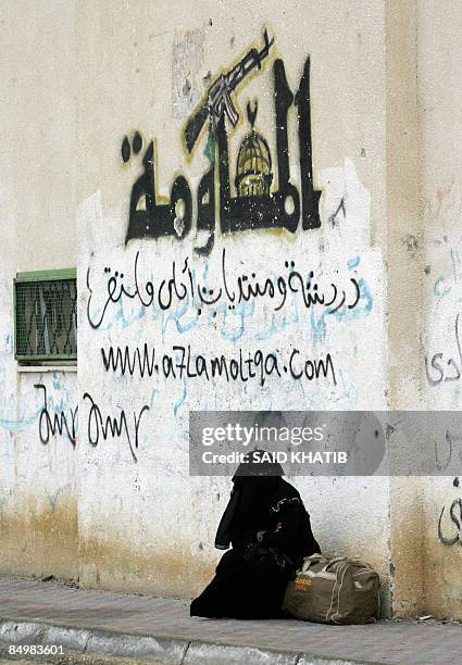 Fully veiled Palestinian woman waits with a bag to cross into Egypt from the southern Gaza Strip border crossing at Rafah on February 22, 2009. The...