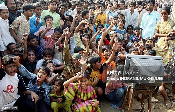 Neighbours of "Slumdog Millionaire" child actor Mohammed Azharuddin cheer as they watch the Oscars on television in Mumbai on February 23, 2009....