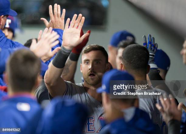 Will Middlebrooks of the Texas Rangers is congratulated by teammates in the dugout after scoring a run on a sacrifice fly by Shin-Soo Choo off of...
