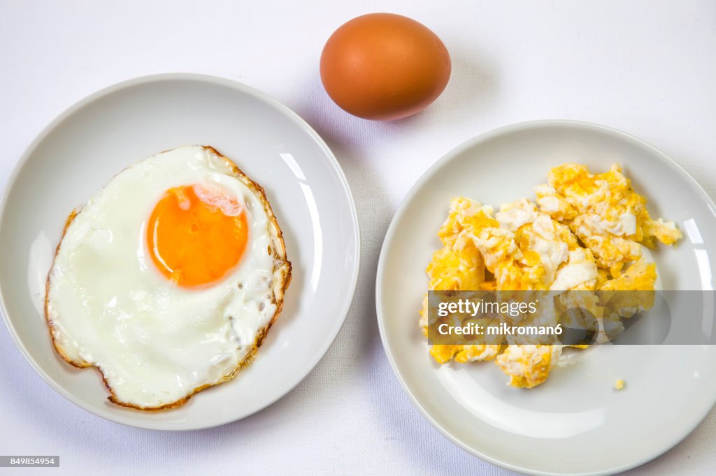 Fried egg on white plate and Scrambled eggs ion white plate for breakfast