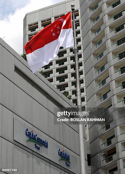 The Singapore flag flies on a pole next to a building with the sign of the CapitaLand subsidiaries company in Singapore on February 19, 2009....