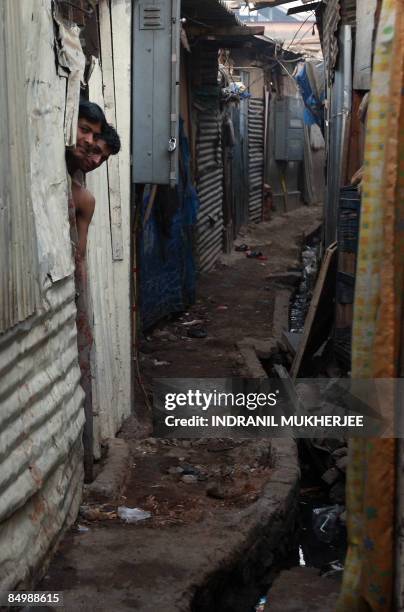 Neighbours look out of their door as media representatives crowd near the shanty of "Slumdog Millionaire" child actor Rubina Ali in Mumbai on...