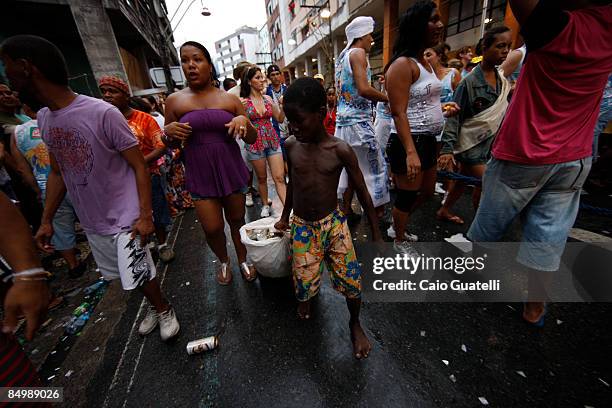 February 22 : A street child collects beer cans, wich he will sell to recycling industries, in the streets of Salvador while carnival groups passes...