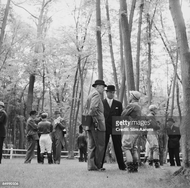 French banker and Baron Guy de Rothschild , holding an umbrella, chatting with his horse trainer and a jockey before the Prix de Diane horse race,...