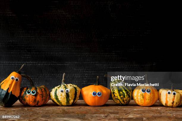 seven pumpkins with eyes in a row for halloween - pumpkin decorating stock pictures, royalty-free photos & images