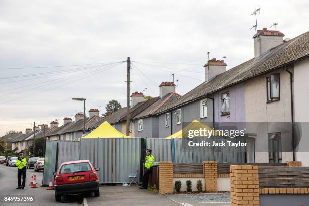 Police officers stand guard by a barrier around a property being searched in connection with the attack on Parsons Green station on September 13,...