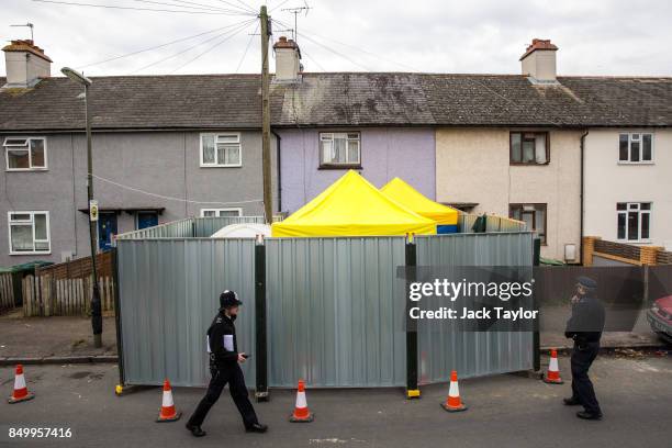 Police officers stand guard by a barrier around a property being searched in connection with the attack on Parsons Green station on September 13,...