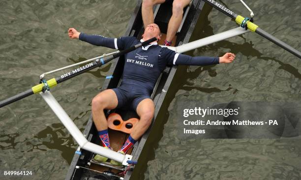 Oxford University's Isis stroke Tom Watson lies down in the boat as he celebrates after his boat wins the reserve Boat Race on the River Thames,...