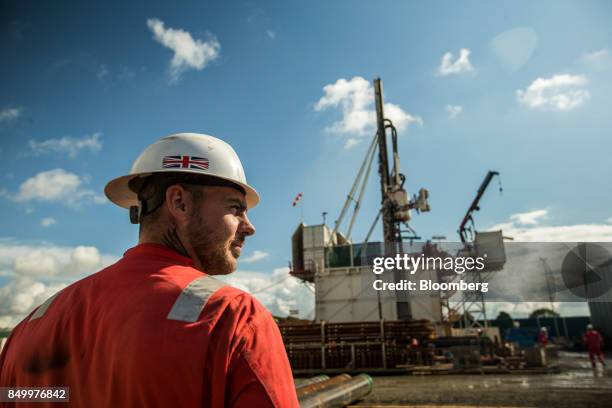 Worker, wearing a hardhat featuring a Union Flag, also known as a Union Jack, stands near the drill rig at the Preston New Road pilot gas well site,...