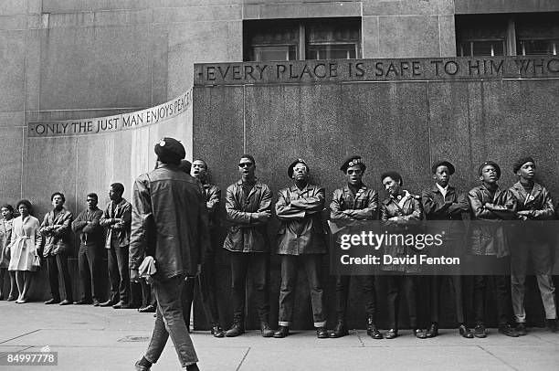 View of a line of Black Panther Party members as they demonstrate, under a pair of engraved quotes, outside the New York County Criminal Court , New...