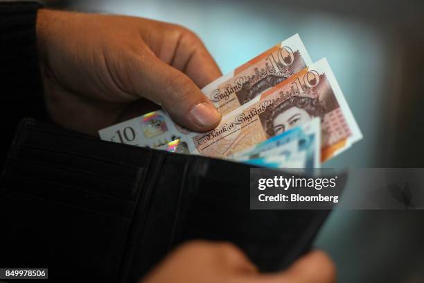 Man removes five and ten pound sterling banknotes from a wallet in this arranged photograph in London, U.K., on Tuesday, Sept. 19, 2017. Strategists...