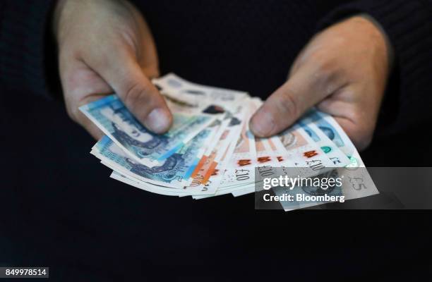 Man holds a selection of five and ten pound sterling banknotes in this arranged photograph in London, U.K., on Tuesday, Sept. 19, 2017. Strategists...