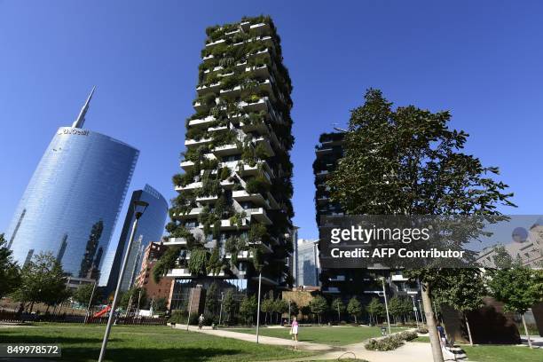 People walk on September 5, 2017 in front of the architectural complex designed by Studio Boeri, the "Bosco Verticale" in the Porta Nuova area in...