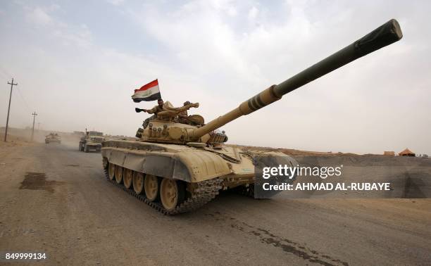 An Iraqi soldier waves his hat from the turret of a Russian-made T-72 tank, as Iraqi forces advance towards the city of al-Sharqat on September 20...