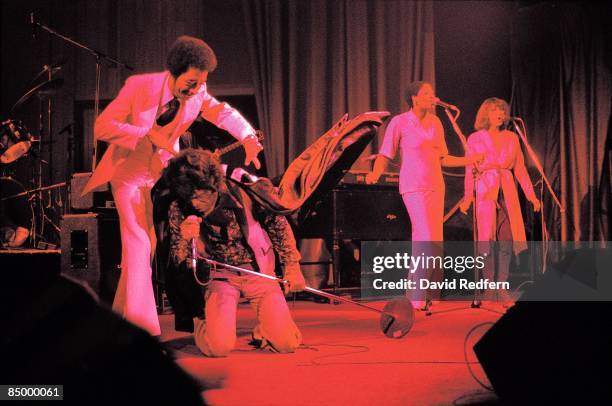American soul singer and songwriter James Brown kneels on stage while the MC places a cape on his back during a performance at The Venue in London in...