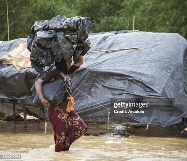 Rohingya Muslim woman, fled from ongoing military operations in Myanmars Rakhine state, carries plastic bags over her head at a refugee camp in Cox's...
