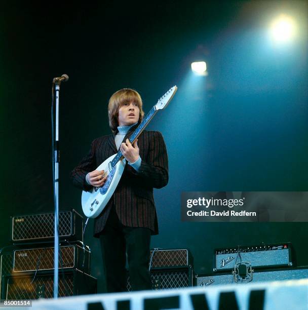 English musician and guitarist Brian Jones of rock group The Rolling Stones plays a Vox Mark VI teardrop guitar on stage with Vox and Fender...