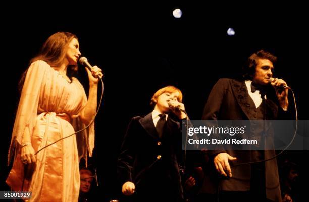 Photo of Johnny CASH and June CARTER and John CARTER CASH; Johnny Cash performing on stage with wife June Carter and son John Carter Cash