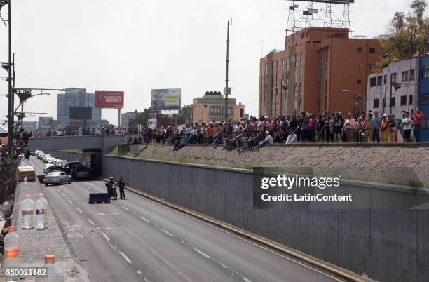 People watch a building knocked down in Viaducto avenue by a magnitude 7.1 earthquake that jolted central Mexico damaging buildings, knocking out...