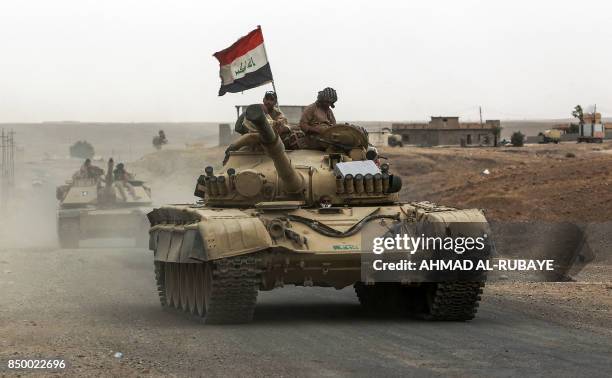 Iraqi soldiers ride atop the turret of a Russian-made T-72 tank, as Iraqi forces advance towards the city of al-Sharqat on September 20 where Iraqi...
