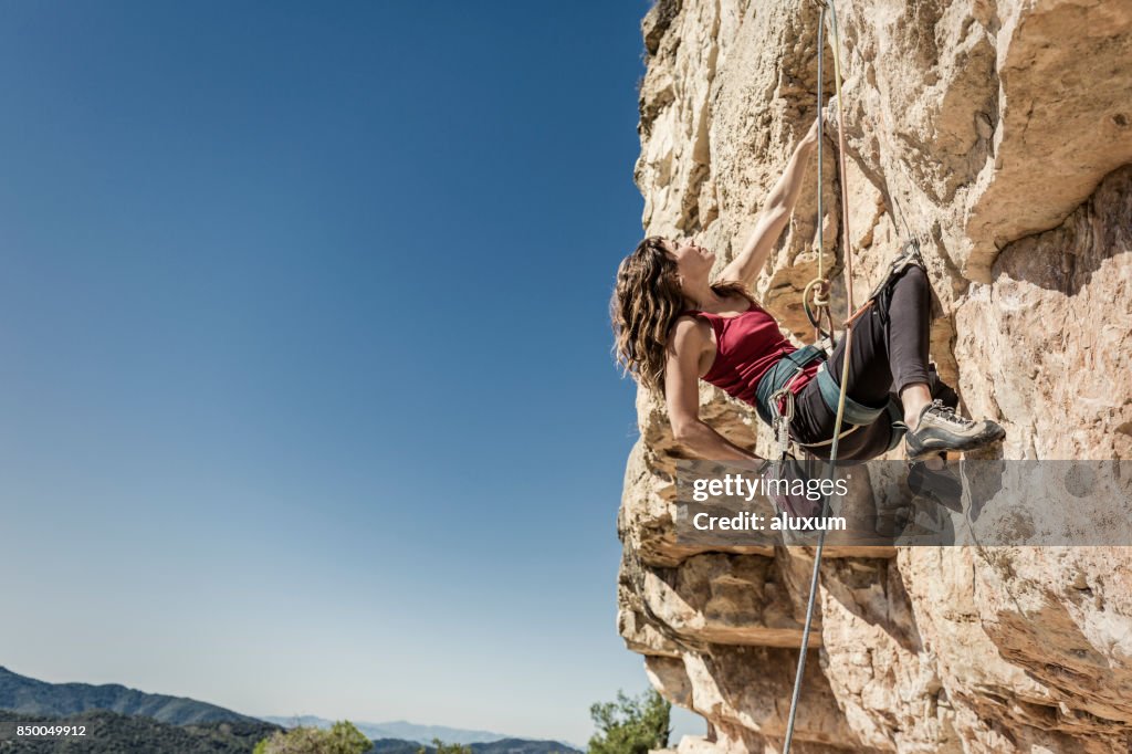 Jeune femme pratiquant l’escalade de rocher