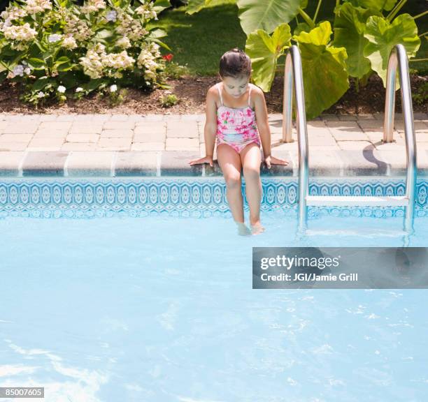 hispanic girl sitting on edge of swimming pool - alleen één meisje stockfoto's en -beelden