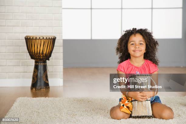 mixed race girl holding drum - instrumentos de percusión fotografías e imágenes de stock