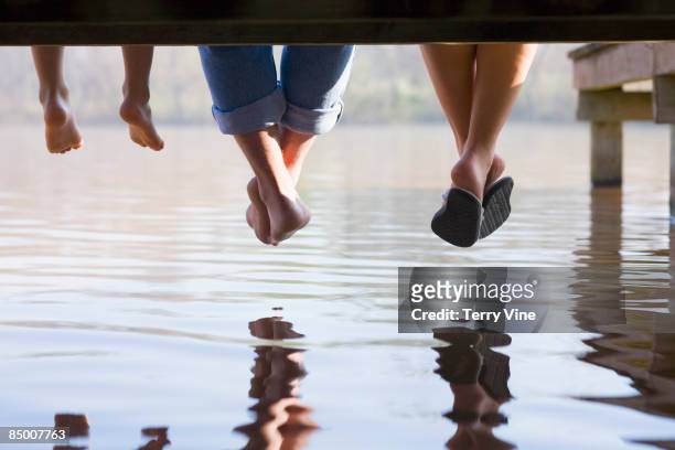 multi-generational men relaxing on boat dock - boy barefoot rear view stock-fotos und bilder