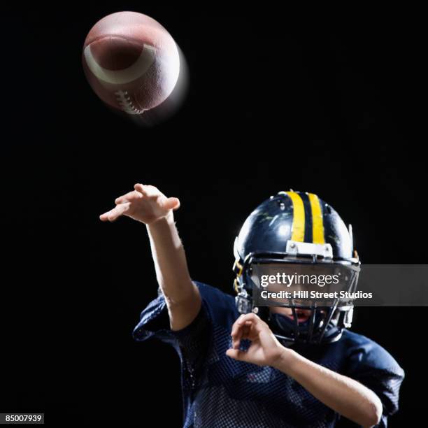 hispanic boy in football uniform throwing ball - throwing football stock pictures, royalty-free photos & images