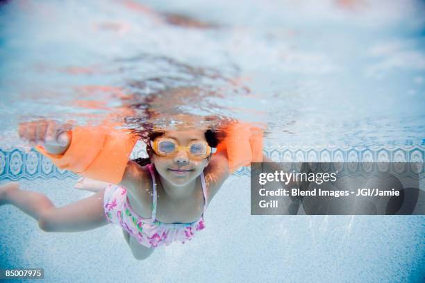 hispanic girl swimming underwater in pool - niño bañandose fotografías e imágenes de stock