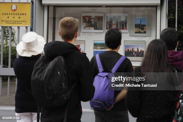 Pedestrians look at photos of various ballistic rocket launches that took places in North Korea which hang on display in front of the main entrance...