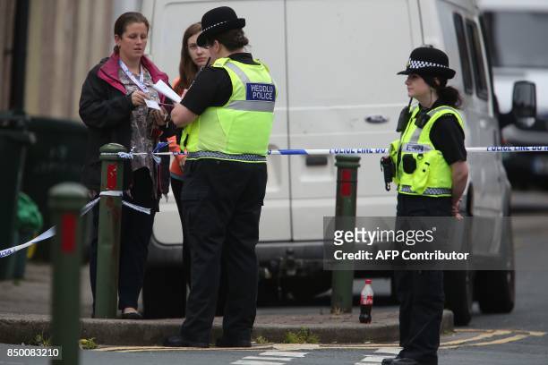 Police officer talks with local residents at a police cordon near to a house in Newport, south Wales, on September 20 as they continue their...