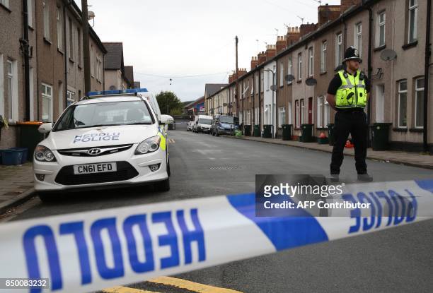 Police officer stands guard at a police cordon near to a house in Newport, south Wales, on September 20 as they continue their investigations into...