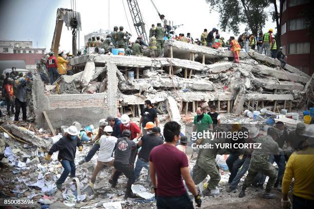 Rescuers, firefighters, policemen, soldiers and volunteers search for survivors in a flattened building in Mexico City on September 20, 2017 a day...