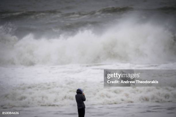 People walk along the beach as high waves produced by Hurricane Jose crash along the shore on September 20, 2017 at Long Island's Smith's Point Beach...
