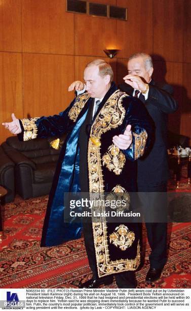 Russian Prime Minister Vladimir Putin wears coat put on by Uzbekistan President Islam Karimov during his visit on August 16, 1999. President Boris...