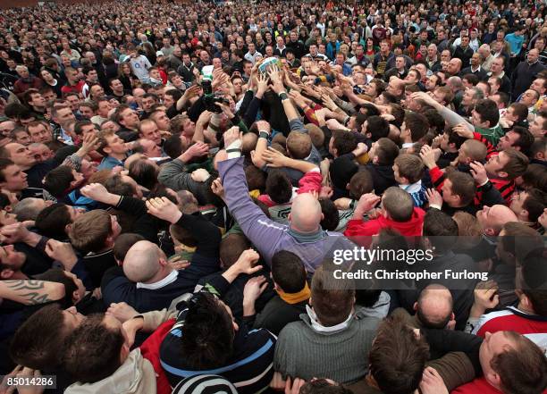 Hands of rival teams Up'ards and Down'ards battle for the ball, which bursts out of the 'hug' under sheer pressure, in the annual Shrove Tuesday 'no...