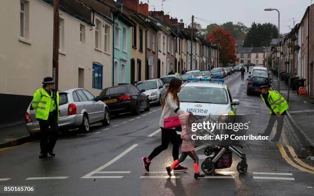 Police officers stand guard at a police cordon near to a house in Newport, south Wales, on September 20 as they continue their investigations into...