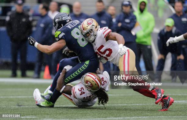 Defensive back Eric Reid, right, of the San Francisco 49ers and linebacker Ray-Ray Armstrong of the San Francisco 49ers tackle tight end Luke Willson...