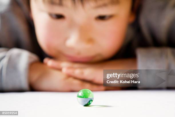 a boy watching a glass marble - glass marble imagens e fotografias de stock