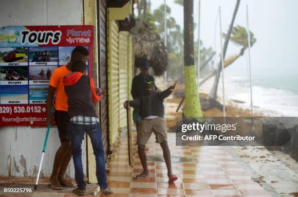 Young men take cover as winds lash the coastal city of Punta Cana, in the Dominican Republic, the eastermost tip of the La Espanola island it shares...