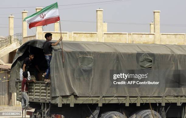 Syrian boy holds the Iranian flag as a truck carrying aid provided by Iran arrives in the eastern city of Deir Ezzor on September 20, 2017 while...